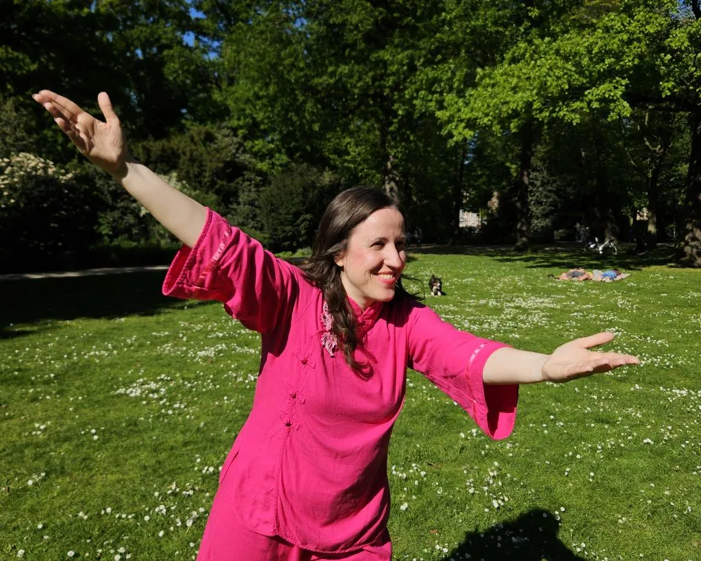 Simone Pohlandt demonstriert die zweite Vorübung „Tasche heben" beim Tai-Chi-Kurs auf der Wiese der Hofgartenkonzerte in Düsseldorf.